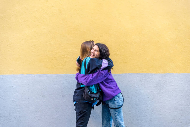 Young friends hugging standing outdoors on the street. Friendship concept. - Φωτογραφία, εικόνα