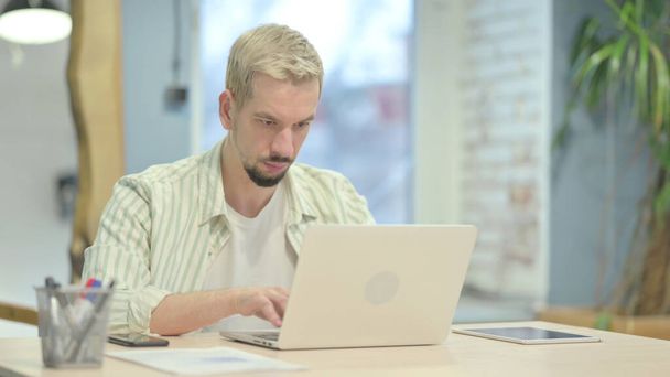 Hombre joven casual escribiendo en el ordenador portátil
 - Foto, imagen