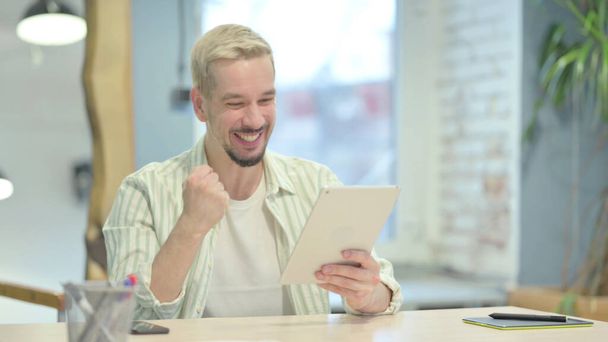 Young Man Celebrating Digital Success on Tablet - Valokuva, kuva