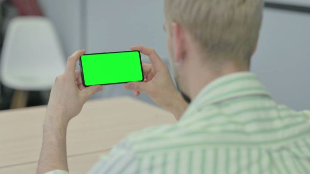 Hombre Sosteniendo Smartphone Horizontal con Pantalla Verde - Foto, Imagen