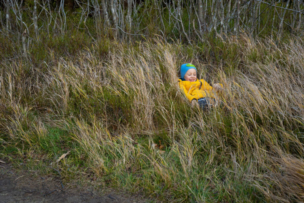 Little kid lying happy in the grass. Fall season - Φωτογραφία, εικόνα