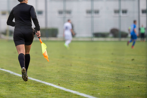 A female assistant referee runs by the touchline during a match  - Фото, изображение