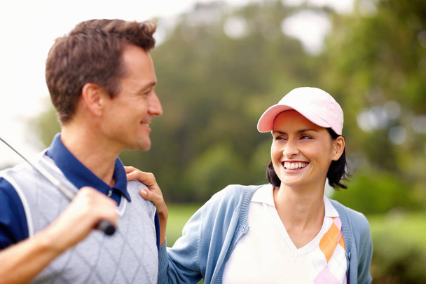 Attractive golfing couple. Attractive golfing couple smiling and looking at each other - Fotografie, Obrázek