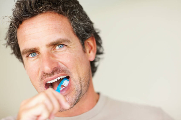Morning routine. Closeup of smart middle aged man brushing his teeth - Foto, afbeelding
