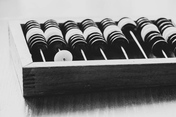 Old wooden abacus for counting money on a wooden table close-up black and white photo - Photo, Image