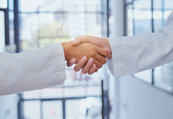 Doctors meeting, shaking hands and partner at hospital with lab coats. Scientist or doctor agree on medical business, support and cooperate together with handshake to show collaboration and teamwork. - Photo, Image