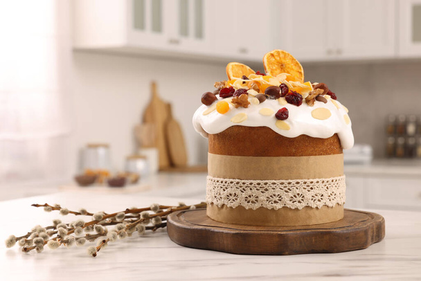 Delicious Easter cake with dried fruits and willow branches on white marble table in kitchen. Space for text - Foto, Bild