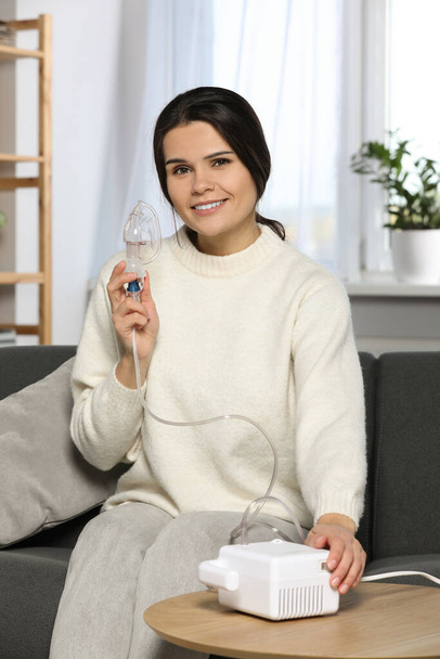 Happy young woman with nebulizer at home - Foto, Imagem