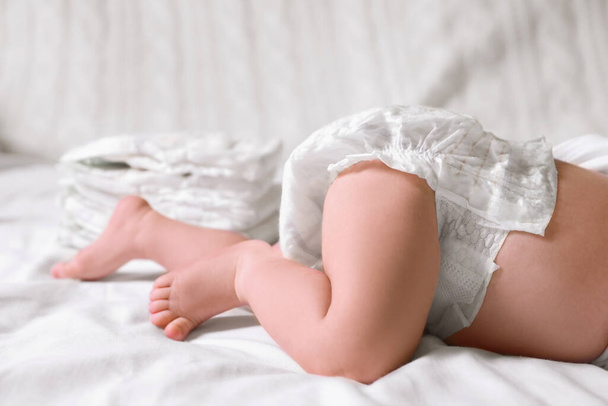 Little baby in diaper lying on bed, closeup - Фото, изображение
