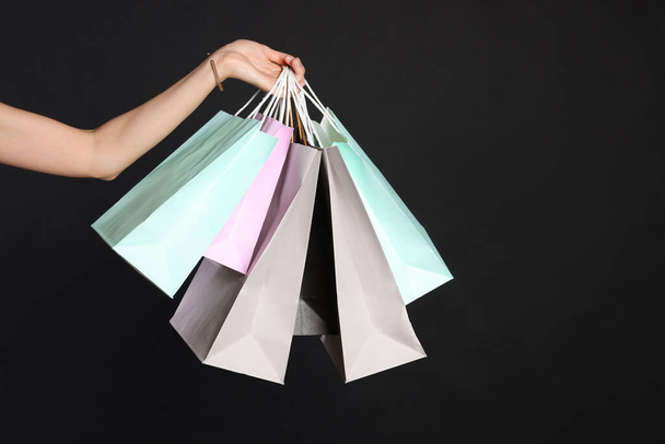 Woman holding shopping bags on black background, closeup. Big sale - Foto, Imagem