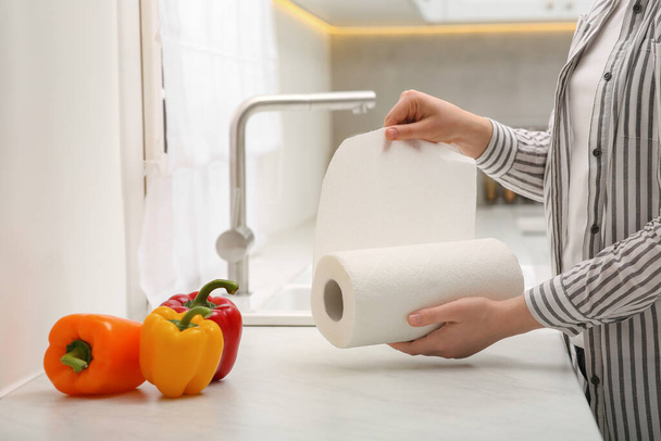 Woman tearing paper towels in kitchen, closeup - Foto, imagen