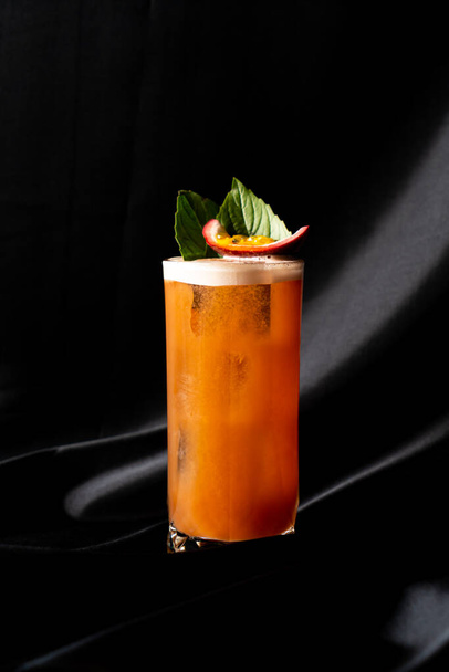 cocktail - infused tequila with basil, passion fruit and cinnamon, lime and mango in glass on dark background - 写真・画像