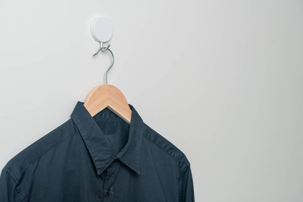 hanging black shirt with wood hanger on wall - Фото, зображення