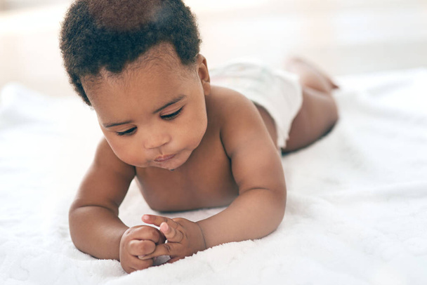 Baby, children and lying with a black baby in the home, blanket on the floor for child development or growth. Kids, cute and innocent with a newborn infant comfortable on a duvet in a house alone. - Photo, Image