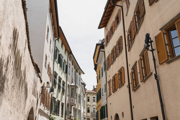 Historic architecture in Italy. Traditional European old town street buildings. Wooden windows, shutters and colourful pastel walls. Aesthetic summer vacation travel background - Photo, Image