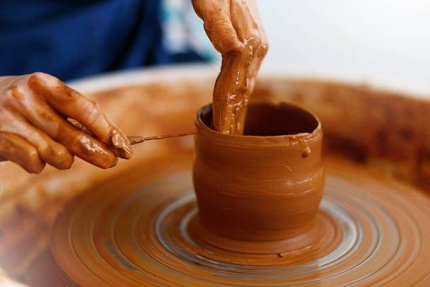 Обрезанное изображение рук, работающих с гончарным колесом, крупным планом формирования глиняных кромок. - Фото, изображение
