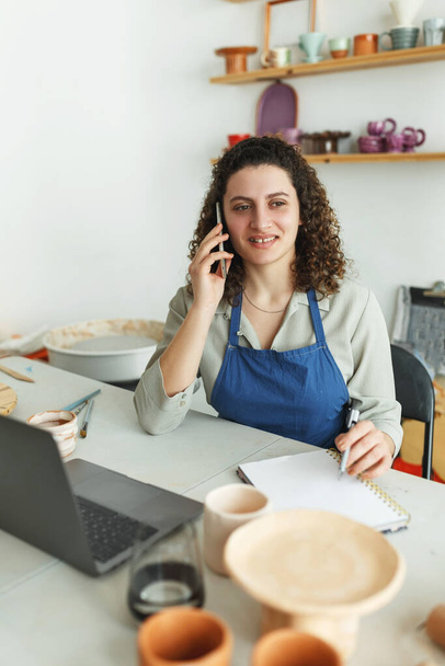 Potter entrepreneur using laptop in workshop, takes orders online - Foto, Bild