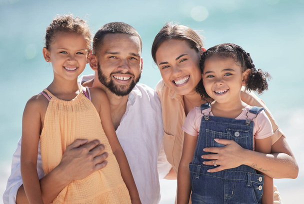 Family, happy at the beach and smile out in the sun while they enjoy and love to spend quality time together. Dad and mom hug kids, they bond and have fun on summer vacation in portrait - Фото, изображение
