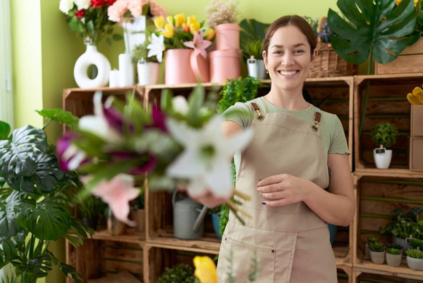 Joven florista hermosa mujer sosteniendo ramo de flores en la tienda de flores - Foto, imagen