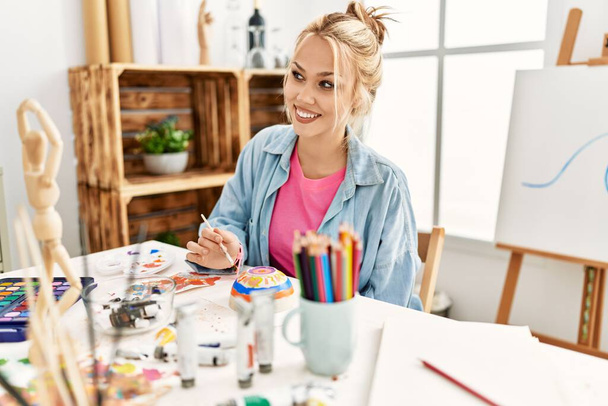 Jovem artista mulher branca sorrindo cerâmica desenho confiante no estúdio de arte - Foto, Imagem