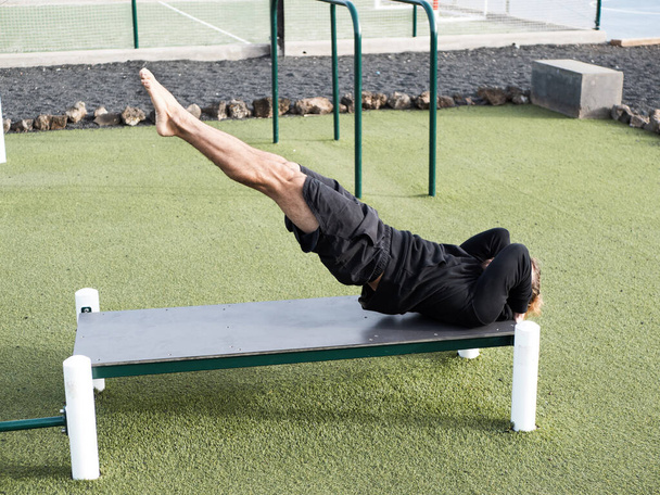 Athlete doing dragon flag abs exercise outdoor at the calisthenics park - Photo, Image