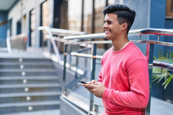 Jeune homme hispanique souriant confiant debout dans la rue - Photo, image