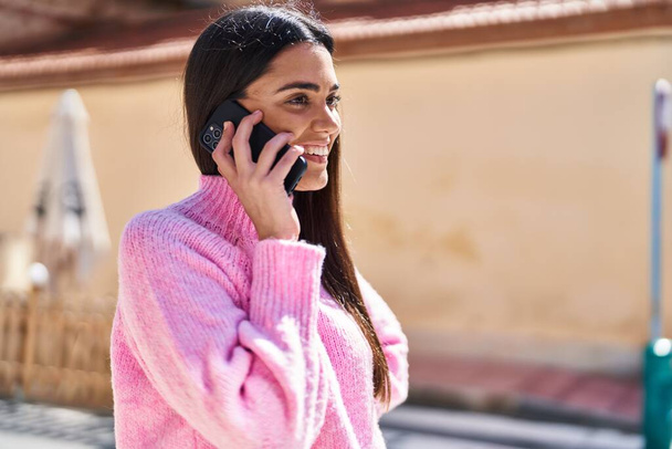 Genç İspanyol kadın gülümsüyor. Kendine güveniyor. Akıllı telefondan konuşuyor. - Fotoğraf, Görsel