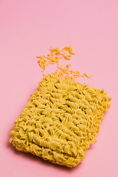 Raw instant noodles on pink paper background with copy space, flatlay. - Zdjęcie, obraz