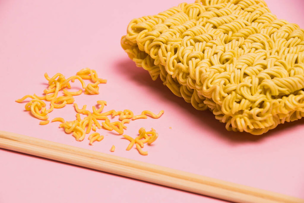 Chopsticks and raw instant noodles on pink background, side view. - Foto, Bild