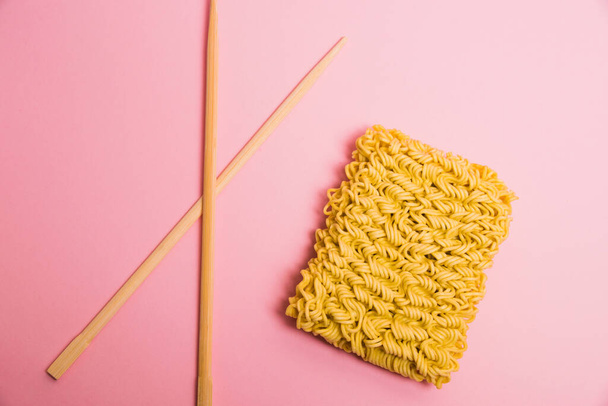 Flatlay, chopsticks and raw instant noodles on pink paper background - Photo, Image