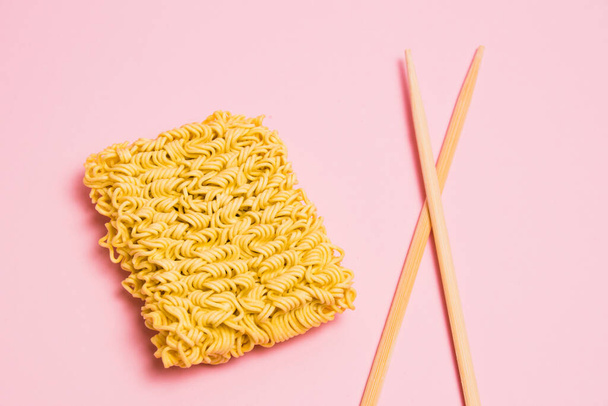 Flatlay, chopsticks and raw instant noodles on pink paper background - Foto, afbeelding