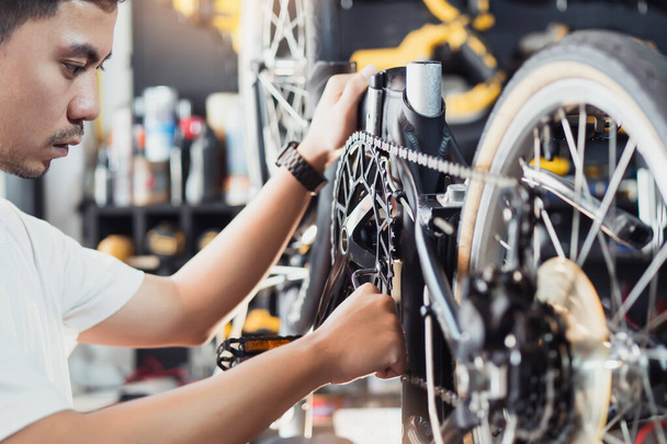 Техник вносит коррективы в Кранксет и ремонтирует коробку передач на складывающемся велосипеде, работающем в мастерской, концепцию ремонта и обслуживания велосипедов - Фото, изображение