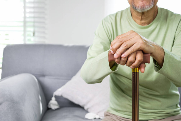 Close up hand of elderly man using walking stick trying to stand and walk at home, Senior man with health problems using walking stick to walk at home - Foto, Bild