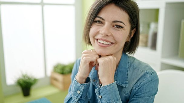 Young caucasian woman smiling confident sitting on table at home - Foto, Imagen
