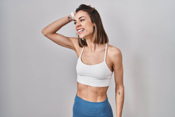 Hispanic woman wearing sportswear over isolated background smiling confident touching hair with hand up gesture, posing attractive and fashionable  - Foto, Bild