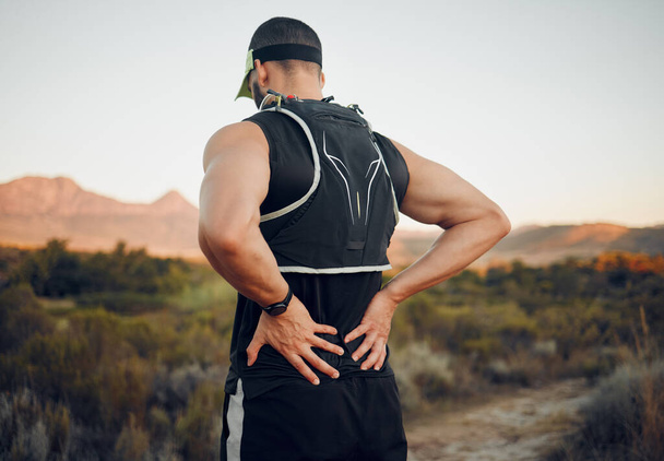 Muscle, injury and back pain after a workout or running outdoor. Man holding lower back muscles in pain after exercise, hike and run. Accident, hurt and physical strain for backache during exercise. - Photo, Image