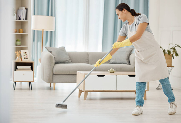 Cleaning, asian girl and sweeping floor with broom for home interior spring clean tidy habit. Housekeeping woman busy with housework in apartment living room for good hygiene lifestyle in house - Photo, Image