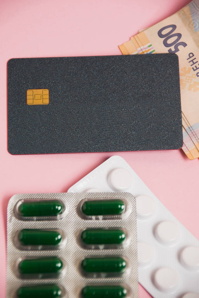 Flatlay, pills, money and bank card on a pink background. Concept of ordering medicine online. - Photo, Image