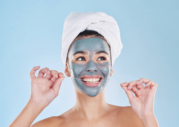 Μάσκα περιποίησης, περιποίηση μαλλιών ή οδοντικό νήμα σε περιποίηση, πολυάσχολη ομορφιά και στούντιο ευεξίας σε μπλε φόντο. Χαμογελάστε, χαρούμενο πρόσωπο ή χαλαρώστε γυναίκα με προϊόν λάσπης προσώπου και δόντια καθαρισμού για υγιή ούλα. - Φωτογραφία, εικόνα