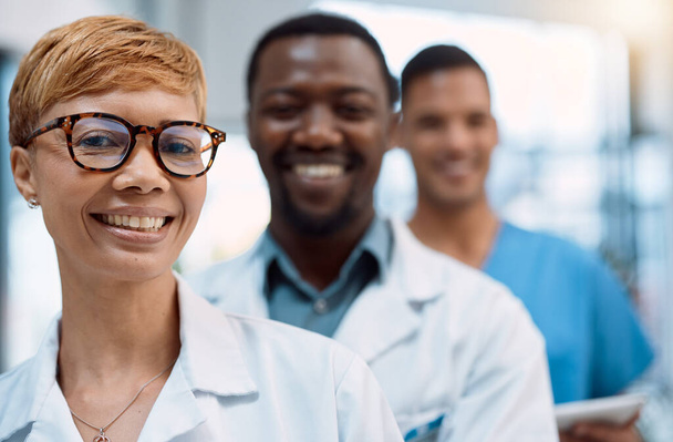 Musta nainen, muotokuva ja lääkärit hymyilevät ryhmätyölle, terveydenhuollon johdolle ja sairaalan johdolle. Ryhmä, onnellinen hoitohenkilökunta ja klinikan yhteistyö, kirurgia luottamus tai lääketieteellinen tuki. - Valokuva, kuva