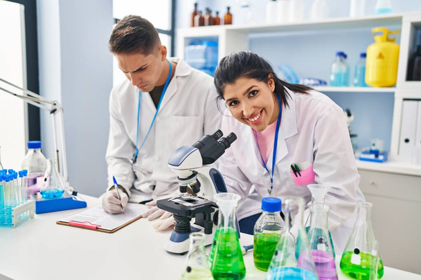 Ученые-мужчины и женщины используют микроскоп для работы в лаборатории - Фото, изображение
