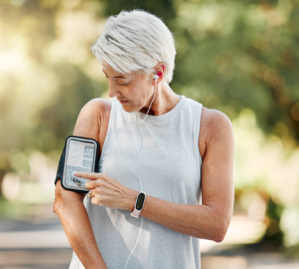Seniorenvrouw met mobiele app voor stappen, fitness en trainingsoefeningen tijdens hardlopen, wandelen of cardiotraining. Ouderdom levensstijl, runner en oudere wellness persoon met gezondheidsdoel. - Foto, afbeelding