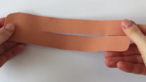 Die Kraft des Kinesio-Tapes für Schmerzlinderung und verbesserte Mobilität. Der ausgeschnittene Aufkleber ist bereit, auf den Körper geklebt zu werden - Filmmaterial, Video
