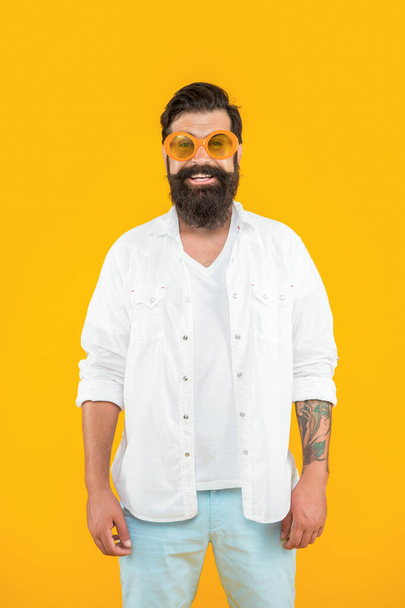 positive cool hipster man isolated on yellow. cool hipster man in studio. cool hipster man on background. photo of cool hipster man wear sunglasses. - Fotoğraf, Görsel