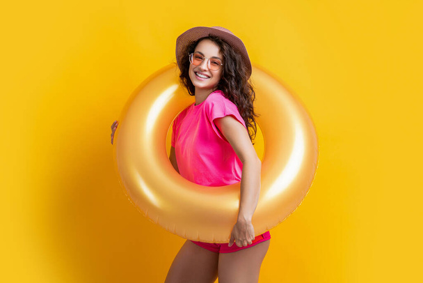 smiling summertime woman with inflatable ring. photo of summertime woman with inflatable ring. summertime woman with inflatable ring isolated on yellow. summertime woman with inflatable ring in studio - Фото, зображення
