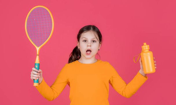amazed kid hold tennis racket and water bottle on pink background. - Photo, Image