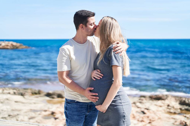 Hombre y mujer pareja esperando bebé besándose en la playa - Foto, Imagen