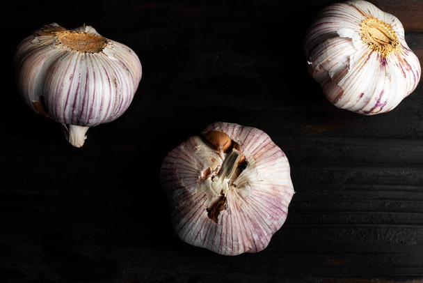 Garlic on black wood background close up, top view, healthy food concept. - Zdjęcie, obraz