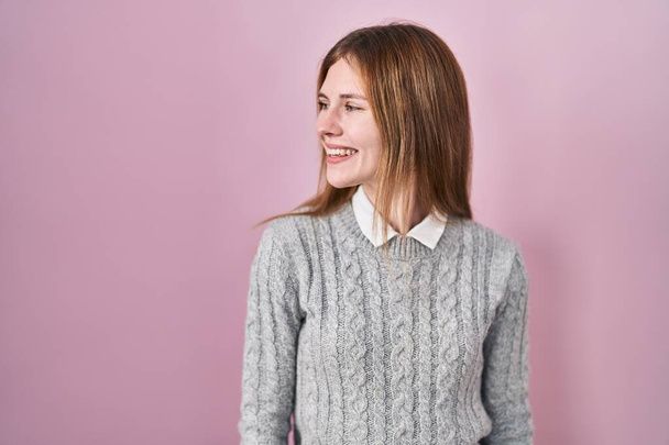 Beautiful woman standing over pink background looking away to side with smile on face, natural expression. laughing confident.  - Fotografie, Obrázek