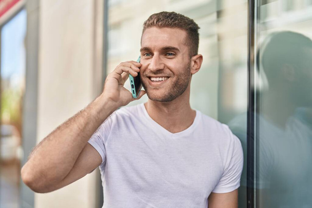 Young caucasian man smiling confident talking on the smartphone at street - Foto, afbeelding